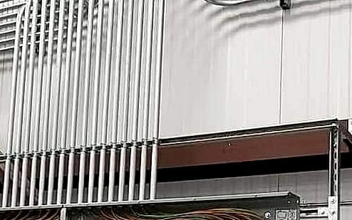 Bank of parallel conduits bent to a matched radius in a sweeping curve into a wall-mounted panel row — precision conduit bending by H&L Professional Services